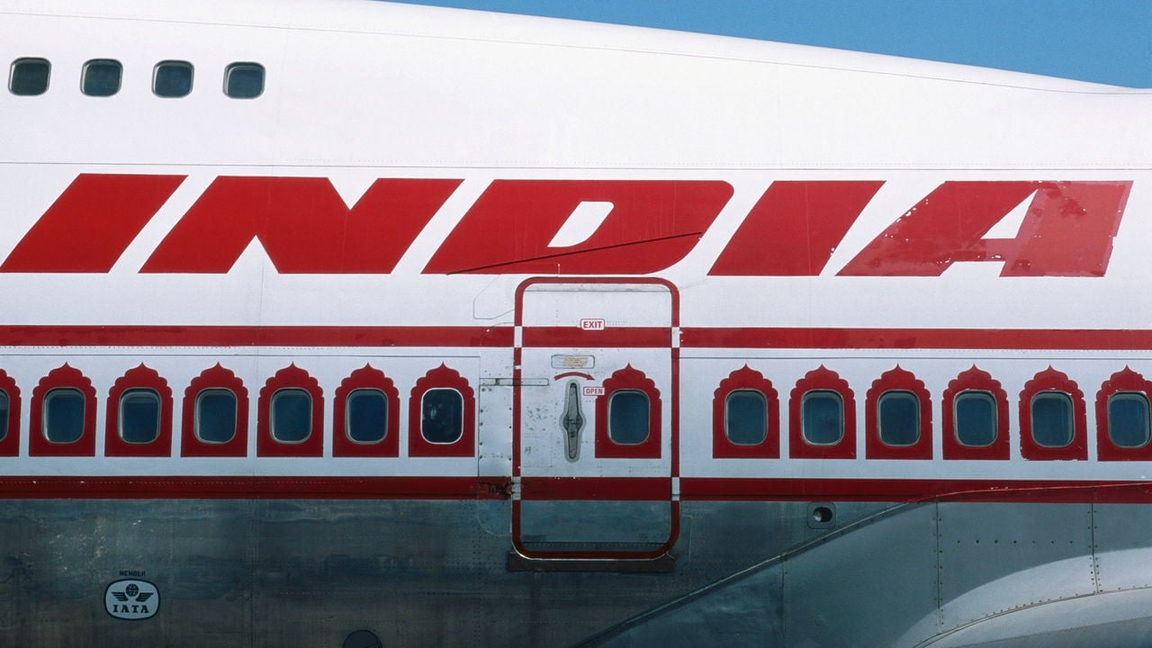 A close up of the word 'India' is seen of the Air India logo and windows on a Boeing 747 aeroplane